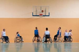 Veteranos de guerra com deficiência, equipes de basquete opostas de raça mista em cadeiras de rodas fotografadas em ação enquanto jogavam uma partida importante em um salão moderno. foto