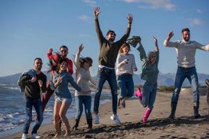 jovens amigos pulando juntos na praia de outono foto