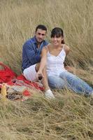 casal feliz desfrutando de piquenique no campo em grama longa foto