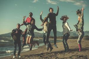 jovens amigos pulando juntos na praia de outono foto