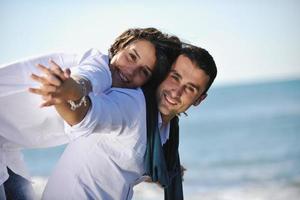 feliz casal jovem se diverte na bela praia foto