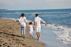 feliz jovem família se divertir na praia foto