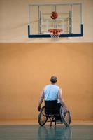 um inválido de guerra em uma cadeira de rodas treina com uma bola em um clube de basquete em treinamento com equipamentos esportivos profissionais para deficientes. o conceito de esporte para pessoas com deficiência foto