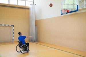 um inválido de guerra em uma cadeira de rodas treina com uma bola em um clube de basquete em treinamento com equipamentos esportivos profissionais para deficientes. o conceito de esporte para pessoas com deficiência foto