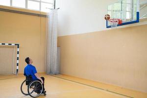 um inválido de guerra em uma cadeira de rodas treina com uma bola em um clube de basquete em treinamento com equipamentos esportivos profissionais para deficientes. o conceito de esporte para pessoas com deficiência foto