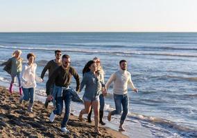 grupo de amigos correndo na praia durante o dia de outono foto