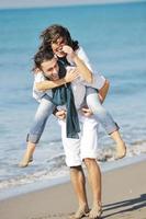 feliz casal jovem se diverte na bela praia foto