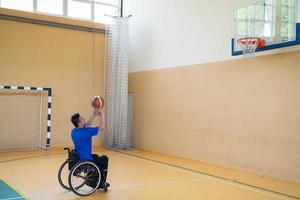 um inválido de guerra em uma cadeira de rodas treina com uma bola em um clube de basquete em treinamento com equipamentos esportivos profissionais para deficientes. o conceito de esporte para pessoas com deficiência foto