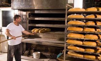 trabalhador de padaria tirando pães recém-assados foto