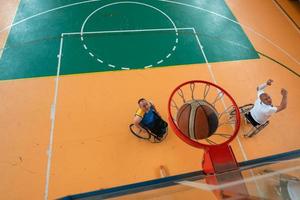 guerra com deficiência ou veteranos de trabalho mistos de raça e idade equipes de basquete em cadeiras de rodas jogando uma partida de treinamento em um ginásio de esportes. conceito de reabilitação e inclusão de pessoas com deficiência. foto