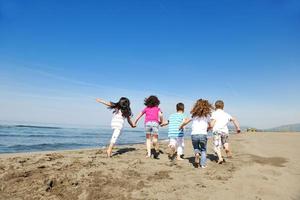 grupo criança feliz jogando na praia foto