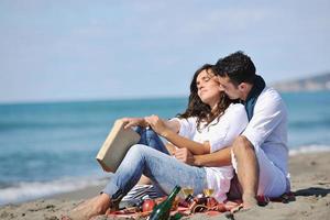 jovem casal desfrutando de piquenique na praia foto