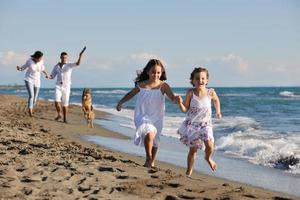 família feliz brincando com cachorro na praia foto