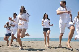 grupo de pessoas felizes se divertir e correr na praia foto