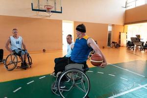 Veteranos de guerra com deficiência equipes de basquete de raça mista e idade em cadeiras de rodas jogando uma partida de treinamento em um ginásio de esportes. conceito de reabilitação e inclusão de pessoas com deficiência foto