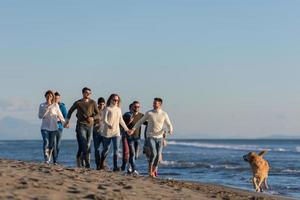 grupo de amigos correndo na praia durante o dia de outono foto