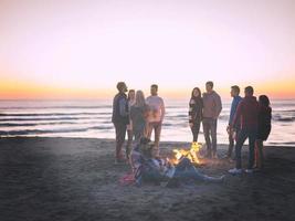 casal curtindo com amigos ao pôr do sol na praia foto