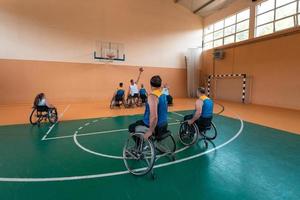 Veteranos de guerra com deficiência equipes de basquete de raça mista e idade em cadeiras de rodas jogando uma partida de treinamento em um ginásio de esportes. conceito de reabilitação e inclusão de pessoas com deficiência foto