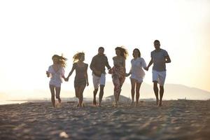 grupo de jovens felizes se divertem na praia foto