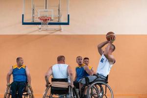 Veteranos de guerra com deficiência equipes de basquete de raça mista e idade em cadeiras de rodas jogando uma partida de treinamento em um ginásio de esportes. conceito de reabilitação e inclusão de pessoas com deficiência foto