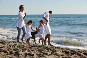 família feliz brincando com cachorro na praia foto