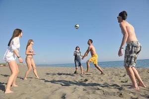 grupo de jovens se diverte e joga vôlei de praia foto