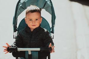 doce menino em uma bicicleta de carrinho ao ar livre. criança em um carrinho de bebê. criança infantil em um carrinho. primavera caminha com crianças. foto