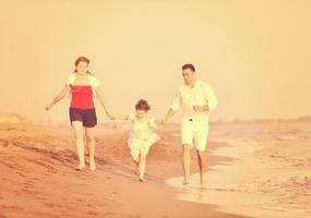 feliz jovem família se divertir na praia foto