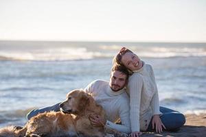 casal com cachorro aproveitando o tempo na praia foto