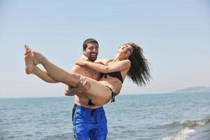 feliz casal jovem se divertir na praia foto