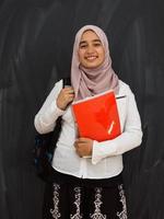 retrato de estudante universitária do Oriente Médio feliz contra lousa preta em sala de aula foto