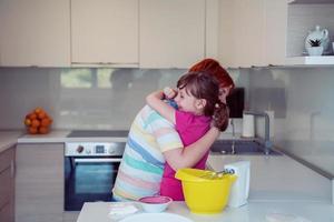 ajudante de garotinha engraçada brincando com massa nas mãos aprendendo a amassar ajuda a mãe adulta na cozinha, a filha do bebê fofo feliz e a mãe dos pais se divertem cozinhando biscoitos. foto