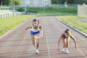 duas meninas correndo na pista de atletismo foto