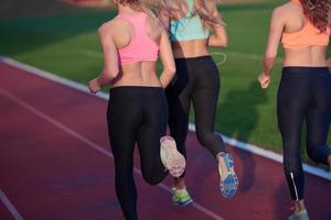 grupo de mulher atleta correndo na pista de atletismo foto