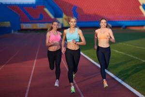 grupo de mulher atleta correndo na pista de atletismo foto