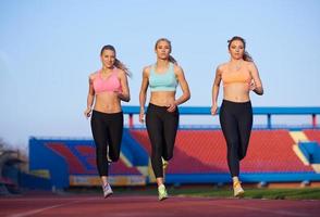 grupo de mulher atleta correndo na pista de atletismo foto