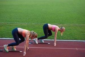 grupo de mulher atleta correndo na pista de atletismo foto