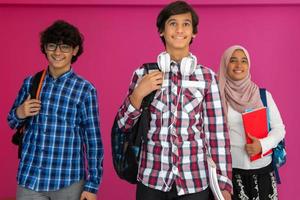 um grupo de adolescentes árabes, uma equipe de estudantes caminhando para o futuro e voltando para a escola o conceito de um fundo rosa. o conceito de educação bem sucedida para os jovens. foco seletivo foto
