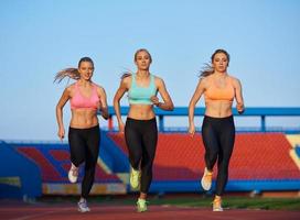 grupo de mulher atleta correndo na pista de atletismo foto