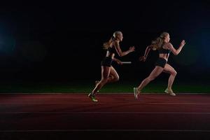 corredores atléticos passando o bastão na corrida de revezamento foto