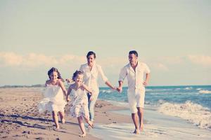 feliz jovem família se divertir na praia foto