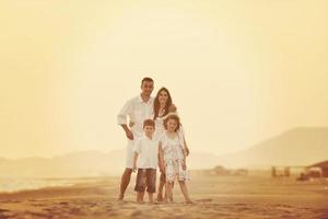 família jovem feliz se diverte na praia ao pôr do sol foto