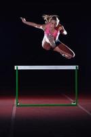 atleta de mulher pulando sobre obstáculos foto