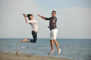 feliz casal jovem se divertir na praia foto