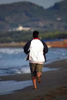 homem correndo na praia foto