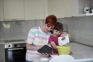 mãe e filha brincando e preparando massa na cozinha. foto