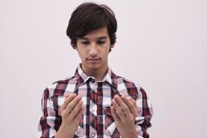 adolescente muçulmano masculino rezando com as mãos abertas foto