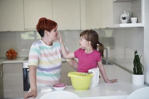 mãe e filha brincando e preparando massa na cozinha. foto