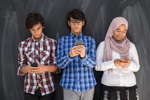 grupo de adolescentes árabes tirando foto de selfie no telefone inteligente com lousa preta no fundo. foco seletivo