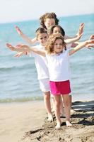 grupo criança feliz jogando na praia foto